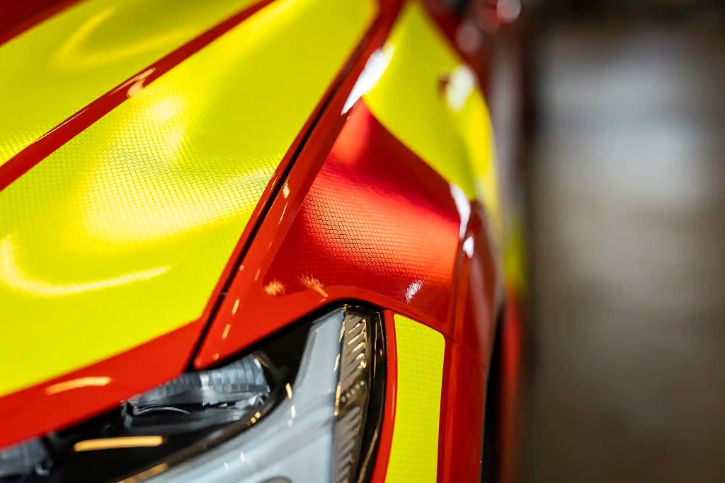 Mikroprismatisk reflexvinyl i orange och blått för battenburgmönster – materialval för hållbar synlighet på arbetsfordon.